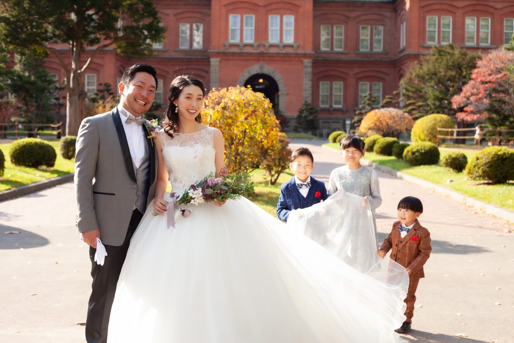 ウェディングドレスとタキシードで家族と記念撮影する新郎新婦